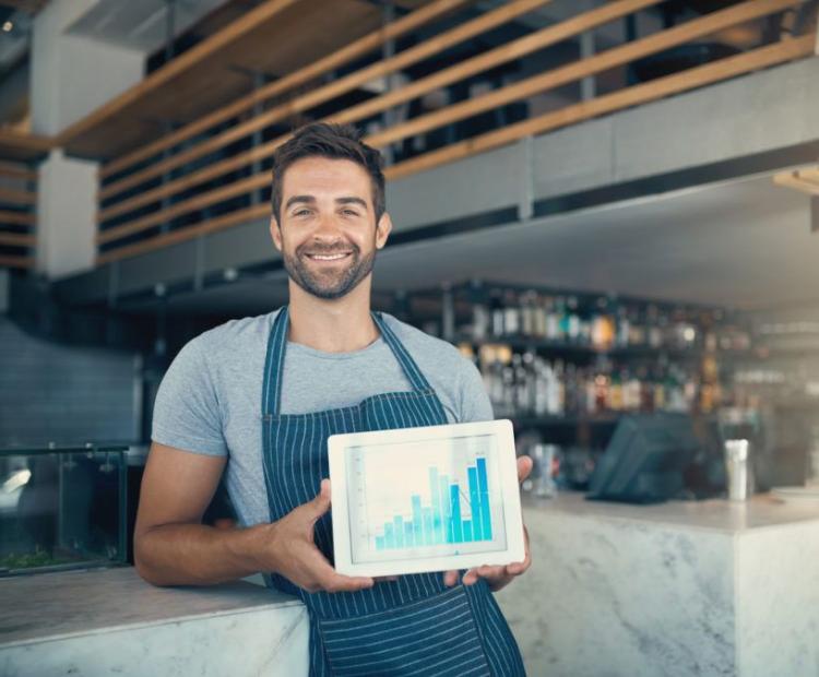 A man with a tab in hand displaying chart with growth pattern