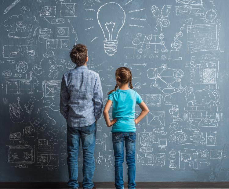two school aged kids looking at board with a lot of ideas and text on it